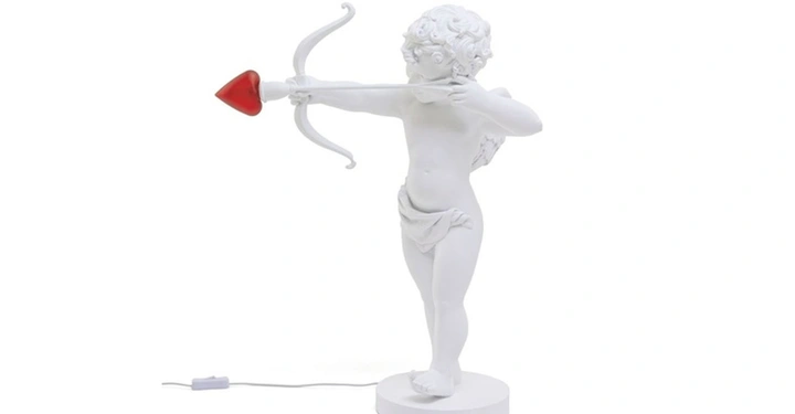 Galerie-Bild 4: Weiße Tischlampe in Form eines Cupidon von Seletti. Stilisierte Engelsfigur mit Bogen, roter Herzpfeil als Glühbirne, originelles Designobjekt für romantische Wohnakzente.