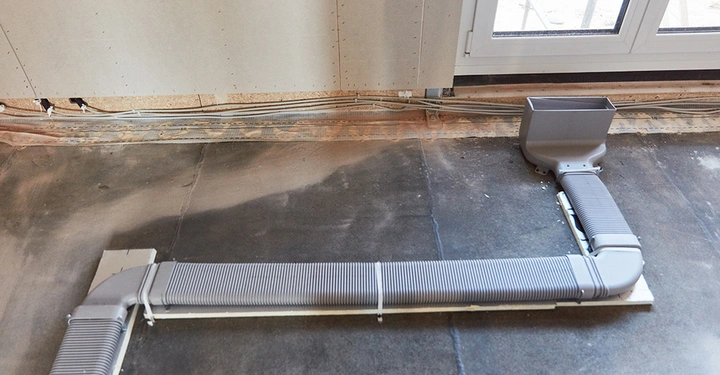 Installation von Flachkanälen auf dem Rohfußboden für eine kontrollierte Wohnraumlüftung zur Sicherstellung guter Raumluft.