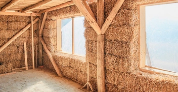 Strohhaus im Rohbau: Innenwände aus Holzständerbauweise mit Stroh ausgestopft. Helle große Fensteröffnungen.