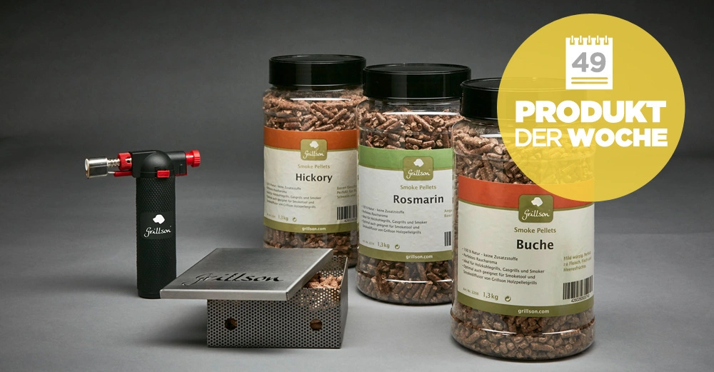 Drei Gläser mit Smoke Pellets Hickory Rosmarin Buche stehen auf einem Tisch neben einem Grillanzünder und einer Metallbox im Hintergrund grauer Hintergrund. Text: Produkt der Woche.