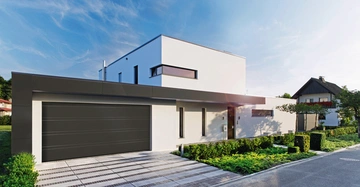 Modernes Haus steht ruhig vor einem Garten mit gepflasterter Einfahrt Garage geschlossen klare Linien Flachdach umgeben von gepflegter Vegetation und benachbarte Gebäude im Hintergrund blauer Himmel