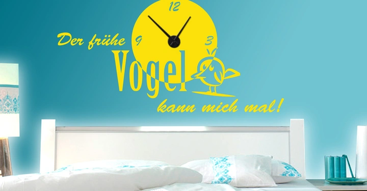 Galerie-Bild 6: Gelbe Wanduhr zeigt 9 Uhr ein Vogel darunter auf blauem Hintergrund oberhalb eines weißen Betts. Text: Der frühe Vogel kann mich mal!
