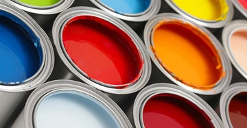 Offene Farbeimer mit bunten Farben stehen nebeneinander.