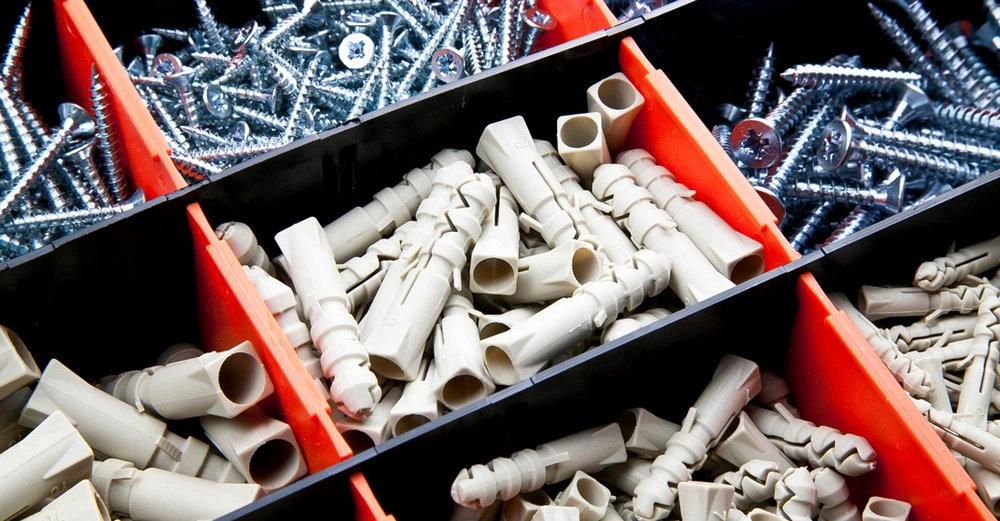 Blick in die Werkzeugkiste, kleine Behälter mit Schrauben unterschiedlicher Art und Größe sowie passenden Dübeln zur Entnahme bereit