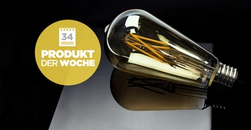 Eine Glühbirne liegt horizontal auf einer schwarzen reflektierenden Oberfläche. Links steht auf einem gelben Kreis Woche 34 Produkt der Woche
