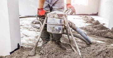 Arbeiter verteilt mit einem Auslaufblock frischen Estrich in einem Innenraum