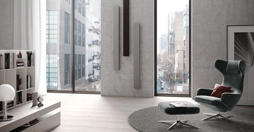 Sessel steht auf Teppich vor großen Fenstern mit Stadtblick Wohnungseinrichtung umfasst Bücherregal Lampe und Kunstwerk Wände und Boden sind in hellen Tönen gehalten moderne urbane Umgebung