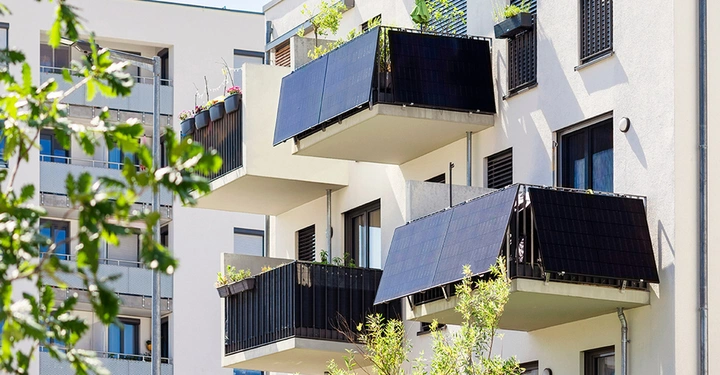 Nachhaltige Balkon-Planung an einem modernen Mehrfamilienhaus, bei der Solarmodule als Balkonkraftwerk direkt in die Balkonbrüstung integriert werden.