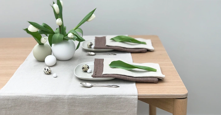 Naturweißer Tischläufer aus Leinen liegt über rustikalem Eichentisch, passend dazu Stoffservietten im gleichen Farbton, ergänzt wird die Tischwäsche durch dunkelgrüne Leinenservietten.