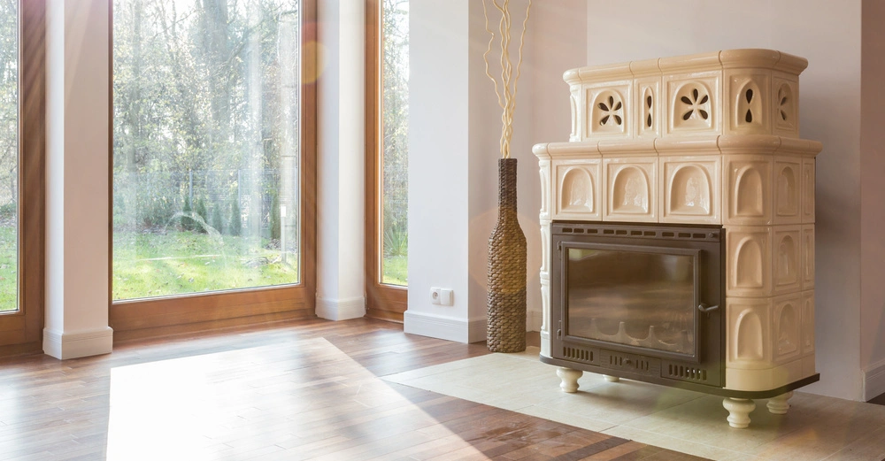 Kamin steht still im modernen Wohnzimmer das große Fenster mit Holzeinfassung und Blick auf grüne Natur umgibt.
