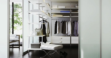 Eleganter und organisierter Kleiderschrank mit Regalen und hängender Kleidung über Schubladen im Kontext eines modernen begehbaren Kleiderschranks mit raumhohen Glaswänden und Blick auf ein grünes Außengelände.