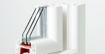 Querschnitt eines weißen PVC-Fensterrahmens mit dreifacher Verglasung in einem hellen, neutralen Raum