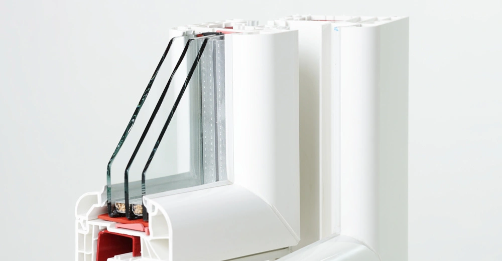 Querschnitt eines weißen PVC-Fensterrahmens mit dreifacher Verglasung in einem hellen, neutralen Raum