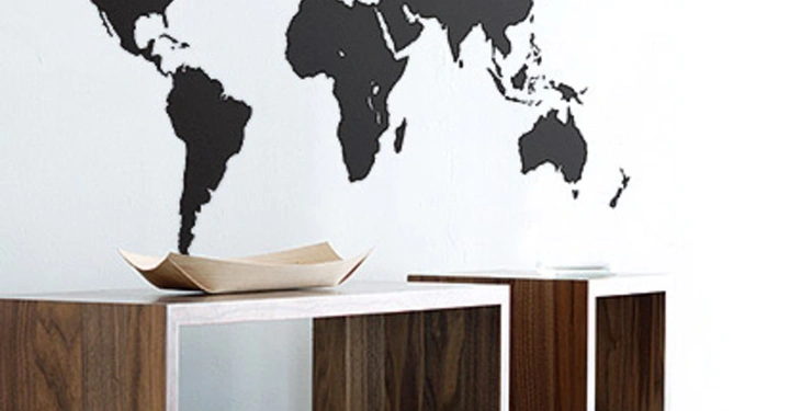 Galerie-Bild 14: Schwarze Weltkarte an der weißen Wand und darunter drei Holzregale zwei davon mit Zeitschriften und Deko-Elementen dekoriert im modernen Raum.