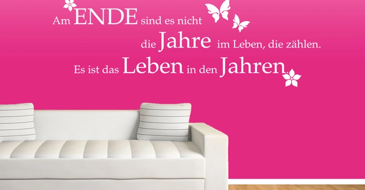 Galerie-Bild 5: Weißes Sofa sitzt vor einer pinken Wand mit folgender Aufschrift Am ENDE sind es nicht die Jahre im Leben, die zählen. Es ist das Leben in den Jahren. Verziert mit Schmetterlingen und Blumen.