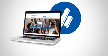 Ein geöffneter Laptop zeigt eine Website im Browserfenster neben einem blauen Kreis mit einem weißen Symbol im leeren hellgrauen Hintergrund. Text Website von Heise RegioConcept professionell erstellen lassen