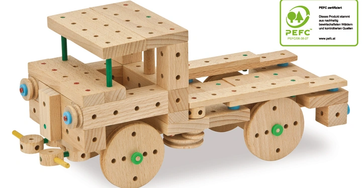 Holzspielzeug-LKW steht still auf weißem Hintergrund. Der LKW hat viele Löcher und bunte Verbindungsstücke. Rechts oben steht PEFC-zertifiziert Dieses Produkt stammt aus nachhaltig bewirtschafteten Wäldern und kontrollierten Quellen PEFC PEFC/06-38-27 www.pefc.at