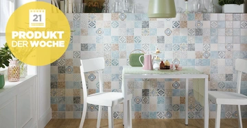 Heller Essbereich mit zwei weißen Stühlen und einem Tisch mit Kuchen auf einer bunte Fliesenwand als Hintergrund Text PRODUKT DER WOCHE 21 in gelber Blase links