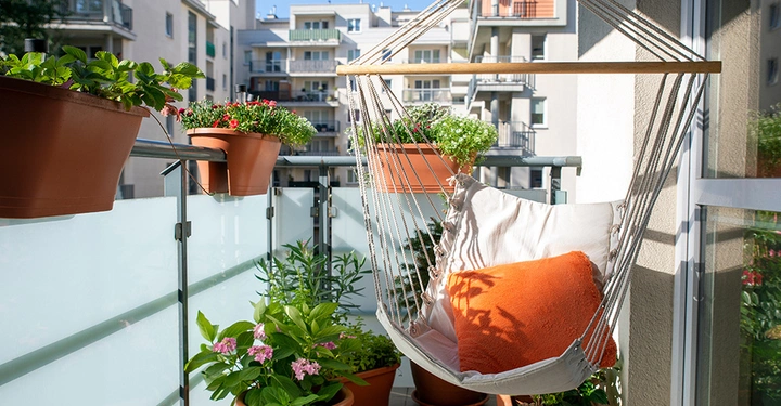 Ein gemütlicher Hängesessel als zentrales Element bei der Balkon-Planung für eine cozy, moderne und entspannte Wohlfühloase mit vielen Pflanzen.