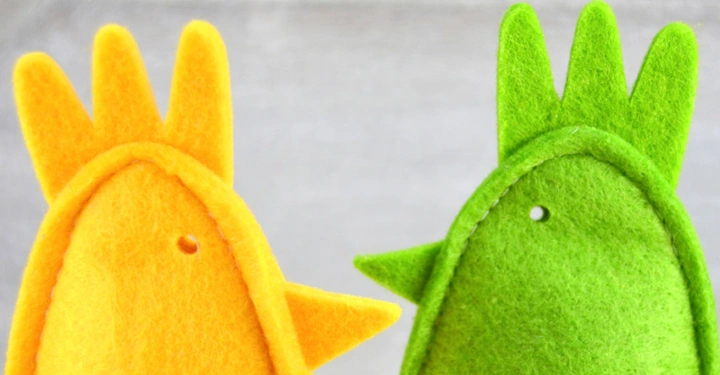 2 Hühnchen aus Filz, einmal gelb einmal grün schauen sich an