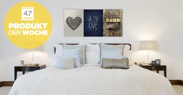 Bett steht in einem hellen Schlafzimmer mit zwei Nachttischen links und rechts und drei Gemälden an der Wand. Gelber Kreis oben links zeigt Text: 47 PRODUKT DER WOCHE.