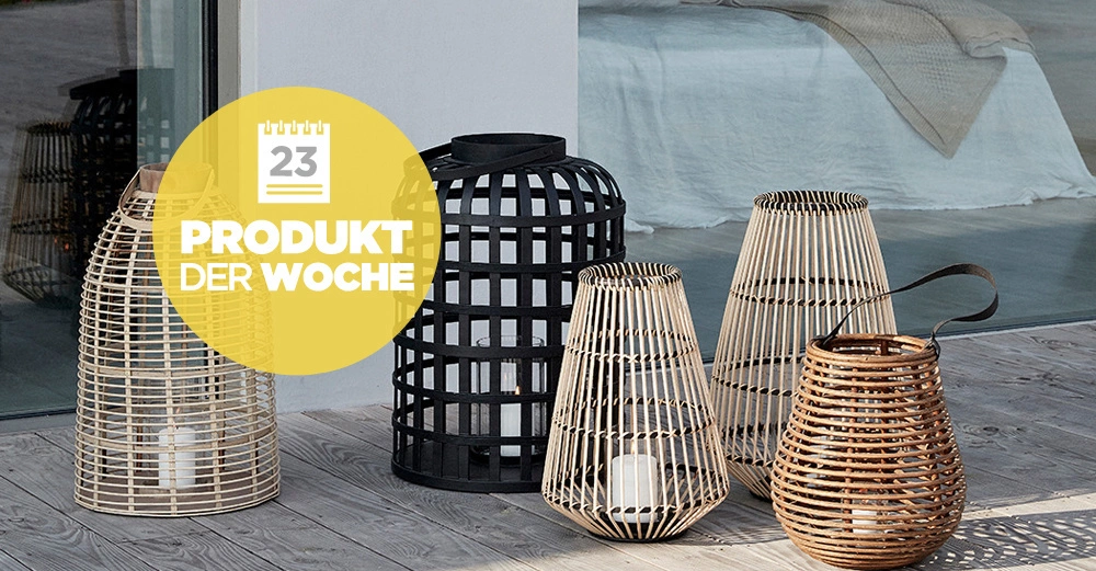 Mehrere Laternen aus Holz und Bambus stehen auf einer Holzterrasse neben einer Glasschiebetür und einem Bett. Gelbes Schild mit Text 23 PRODUKT DER WOCHE.