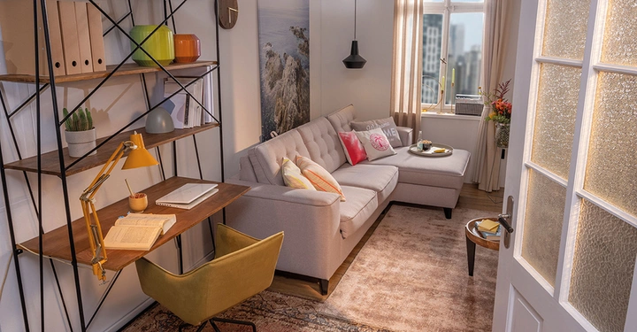 Ein graues Sofa steht in einem gemütlichen Wohnzimmer vor einem Fenster in einer Stadt. Ein Schreibtisch mit Laptop und Buch ist neben einem Regal mit Ordnern und Deko.