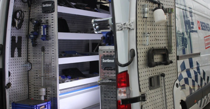 Galerie-Bild 15: Werkzeug und Ausrüstung sind ordentlich in Regalen und an Wänden eines geöffneten Lieferwagens verstaut Sortimo-Logo sichtbar Umgebung zeigt leeren Parkplatz bei Tageslicht