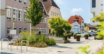 Innenstadt mit Pflasterung, Grünpflanzen und wenig Asphalt.