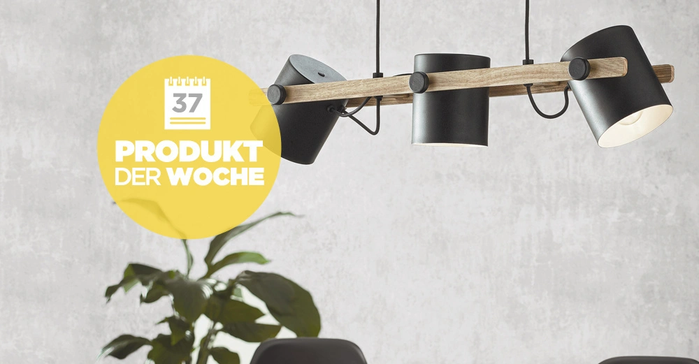 Eine moderne Hängelampe mit schwarzem Metall und Holzbalken hängt in einem minimalistischen Raum vor einer grauen Wand über schwarzen Stühlen mit einer Pflanze im Hintergrund. Text: "37 Produkt der Woche".