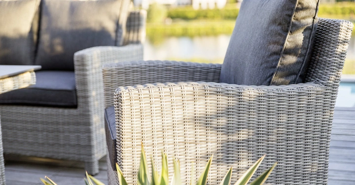 Galerie-Bild 3: Geflechtstuhl steht auf einer Terrasse neben einer Pflanze Ruhebereich mit anderen Sitzgelegenheiten im Hintergrund Bei sonnigem Wetter ist ein ruhiger Teich und Wohnhäuser in der Ferne zu sehen