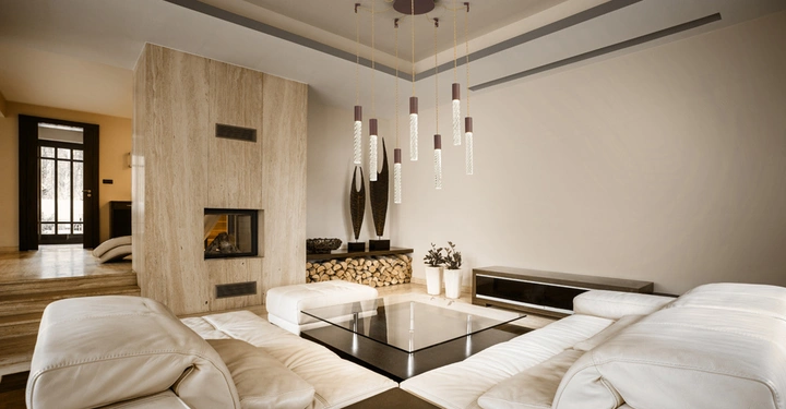 Helle Ledersofas umgeben einen Glastisch modernes Wohnzimmer ein Kamin in der Wand eingelassen mit Holzscheiten darunter dekorative Hängelampen an der Decke schwarzer TV-Tisch an der Wand Hintergrund