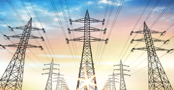 Stromtrasse mit Stromleitungen vor dem Abendhimmel