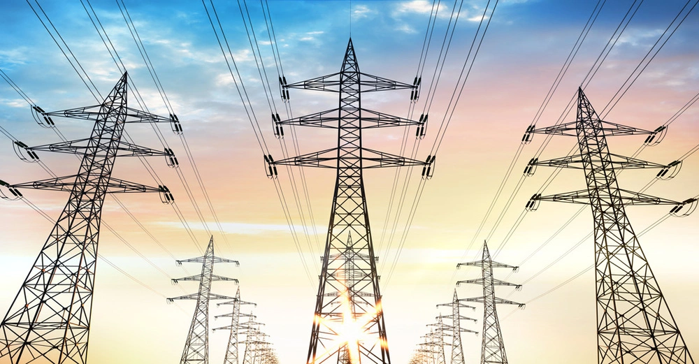 Stromtrasse mit Stromleitungen vor dem Abendhimmel