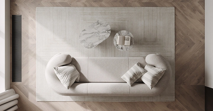 Galerie-Bild 2: Vogelperspektive auf ein geschwungenes Designer-Sofa und Marmortische auf Fischgrätparkett im luftigen Stil der Pantone Farbe Cloud Dancer.