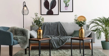 Ein modernes Wohnzimmer mit grauem Sofa und goldenen Vasen als Highlights.