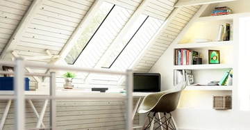 Schreibtisch mit Laptop und Blumentopf steht in einem hellen Dachbodenbüro beleuchtet durch schräge Fenster mit Bücherregalen an der rechten Wand.