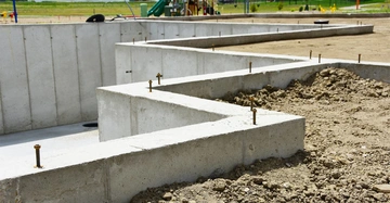 Betonfundament wird gebaut Baustelle mit Spielsplatz im Hintergrund