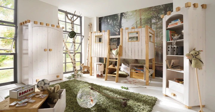 Galerie-Bild 8: Holz-Etagenbett mit Leiter in einem Kinderzimmer mit weißer Einrichtung und Waldtapete im Hintergrund. Spielzeug auf Teppich und Möbeln. Ein Fischglas steht auf einem grünen Teppich. Text im Bild: DOMINO