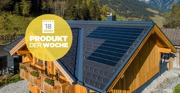 Ein Holzhaus mit Solarpaneelen auf dem Dach steht in einer bergigen Landschaft mit grünen Bäumen und schneebedeckten Bergen im Hintergrund. Text: 18 PRODUKT DER WOCHE