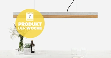 Eine längliche Hängelampe leuchtet über einem Tisch mit zwei Glasgefäßen, einer Vase voller Blumen und einer kleinen Pflanze in einem quadratischen Topf. Text: 7 PRODUKT DER WOCHE