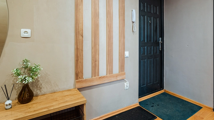 enger Vorraum mit hellgrauen Wänden und Wandbeleuchtungs-Element aus Holz