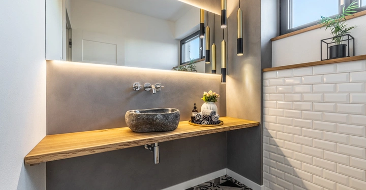 Galerie-Bild 4: Ein Waschbecken steht auf einer hölzernen Arbeitsplatte in einem modern eingerichteten Badezimmer mit grauer Wand und geometrisch gemustertem Boden. LA MURISTA