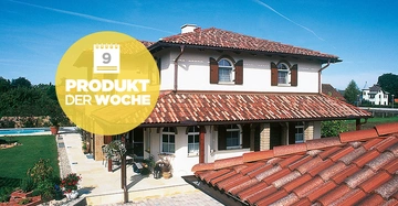 Zweistöckiges Haus mit roten Ziegeldach und weißen Wänden steht inmitten eines grünen Gartens. Text im gelben Kreis: 9 PRODUKT DER WOCHE. Mehrere Bäume und Häuser im Hintergrund.