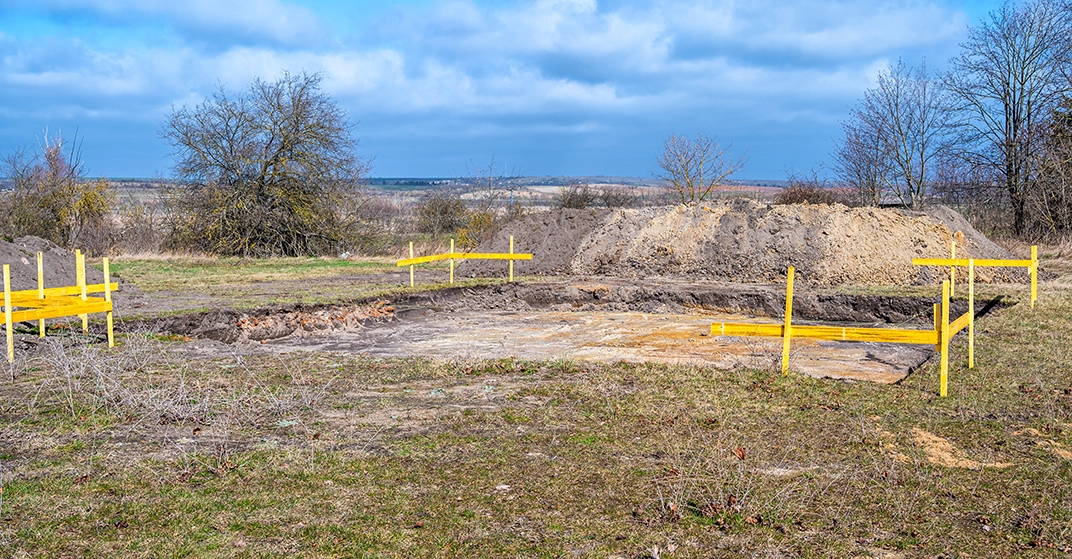 Planum für Bodenplatte mit gelben Absicherungszäunen vor blauem Himmel