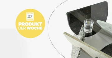 Glas Wasser ruht auf modernem Tisch aus geometrischen Steinformen in hellem Raum; gelber Kreis links mit Kalender- und Textgrafik mit 27 PRODUKT DER WOCHE.