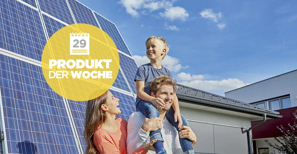 Ein Mann trägt ein Kind auf den Schultern im Freien neben einer Frau lächelnd vor einem Haus mit Solarpaneelen. Text auf gelbem Kreis 29 PRODUKT DER WOCHE