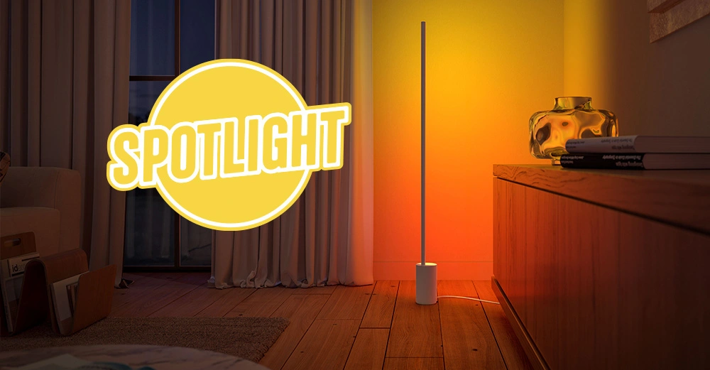 Smarte Stehleuchte von Signe Philips Hue steht in Wohnzimmer und erleuchtet den Raum in warmen Orange- und Rottönen. Logo SPOTLIGHT schräg über Foto. 