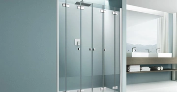 Dusche mit Glastüren steht in modernem Badezimmer mit Doppelwaschbecken Holzablage und Fensterausblick auf Berge helle Fliesen und blaue Wandgestaltung