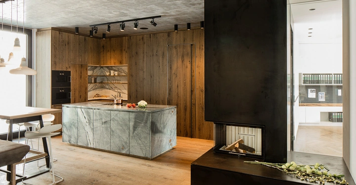 Insel mit Obst und Messer darauf in eleganter moderner Küche mit Holzschränken und Kamin daneben in einem stilvoll eingerichteten Apartment